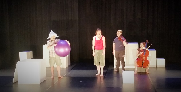 A stage scene from Emily Loves to Bounce with performers, a cellist and a large purple ball